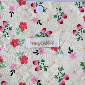 Detailed close-up of floral quilted fabric texture with a button and brand woven label