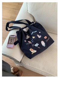 Detailed view of navy canvas tote bag featuring cute cat and cupcake embroidery