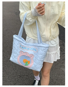 Close-up of light blue quilted heart tote bag with I am a Fish embroidery detail
