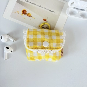Detail of yellow gingham earphone case with white lace trim and metal hanging ring