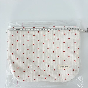 Detail showing the 25cm width measurement of the cream heart embroidered makeup bag