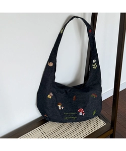 Détail de broderie forestière avec champignons et coccinelle sur sac hobo en jean