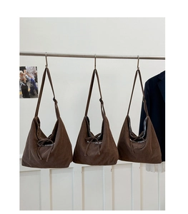 Three brown corduroy hobo bags with white text hanging on a minimal display rack