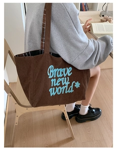 Detail of dark brown corduroy tote bag with blue 'Brave New World' embroidery and floral pattern