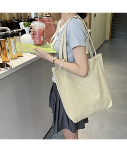 Beige canvas tote bag shown on model in a street style setting for daily shopping