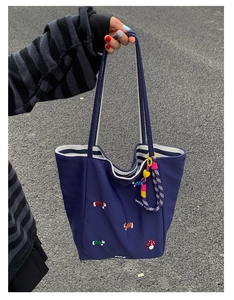 Detail of mushroom and dog embroidery on navy tote bag with yellow heart charm