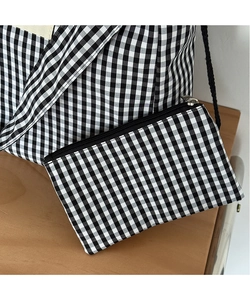 Detail of checkered canvas coin purse with zipper and lanyard on a wooden desk