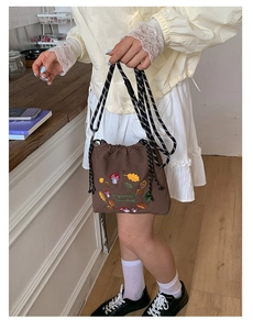 Detailed close-up of brown nylon crossbody bag with colorful mushroom embroidery and woven strap