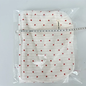 Measuring the width of a striped heart knit makeup bag inside its clear packaging