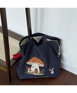 Detail of mushroom and bunny embroidery on navy tote bag with red handle and drawstring