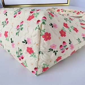 Detailed close-up of quilted floral lunch bag with strawberry print and bottom seam
