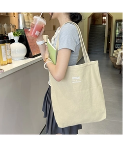 Beige canvas tote bag with YEYUBAG minimalist print shown in a modern lifestyle setting