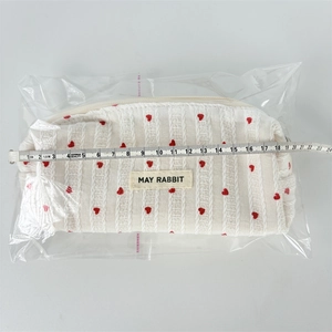 Detail showing red heart pattern fabric texture and May Rabbit label on a white bag