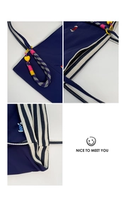Detail of dark blue canvas bag featuring striped handles and colorful dog embroidery