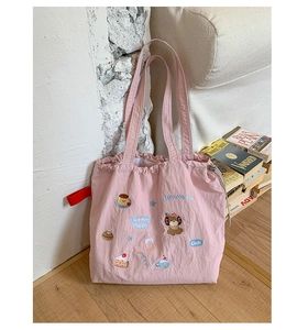 Detail of pink embroidered drawstring tote bag with cute puppy and pudding pattern