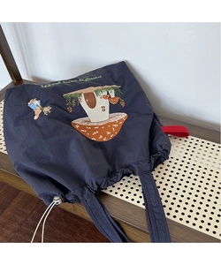 Detail of mushroom house and rabbit embroidery on blue canvas drawstring tote bag