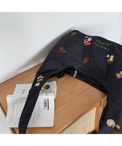 Détail de broderie de forêt avec champignon et marguerite sur sac bandoulière en denim