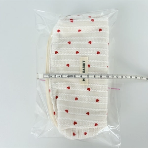 Measuring heart pattern knit makeup pouch with a ruler showing the width of 18cm