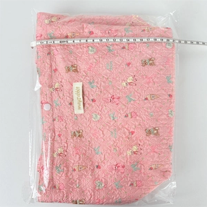 Close-up of pink quilted floral lunch bag with bear print and size measurement tape