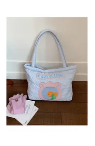 Detailed view of heart quilted pattern and fish embroidery on light blue tote bag