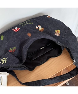 Détail des motifs de champignons brodés et de la poche intérieure spacieuse de ce sac en denim