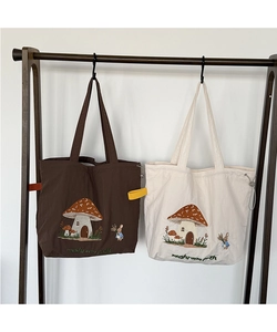 Close-up of mushroom house and rabbit embroidery on premium canvas tote bags