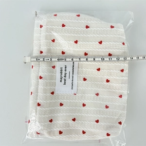 Detail of cream striped cosmetic bag with red heart embroidery and size measurement