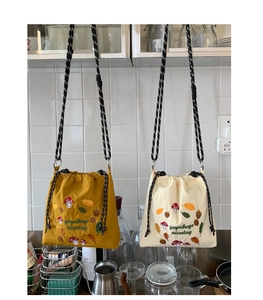 Detail of embroidered forest patterns on nylon crossbody bags in ginger and beige
