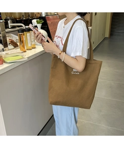 Close-up of brown canvas tote bag with white text detail in a cozy cafe setting
