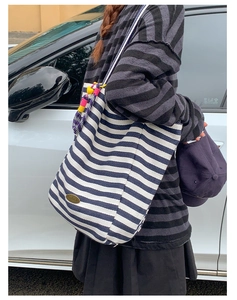 Detail of blue striped canvas tote with handmade metal tag and colorful beaded tassel