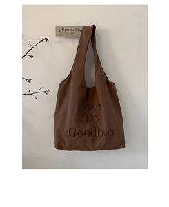 Detail of brown canvas tote bag with embroidered Never Say Goodbye slogan and wide strap