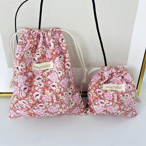Close-up of pink floral drawstring storage bags in two sizes with sturdy cotton texture