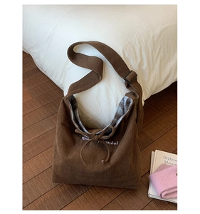 Detail of dark brown corduroy shoulder bag with embroidery and adjustable strap