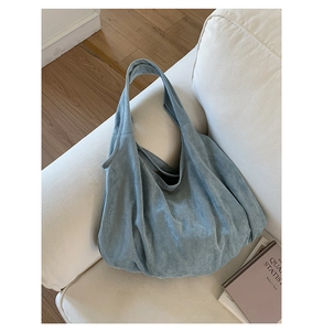 Detail of misty blue suede hobo bag fabric texture on white sofa background