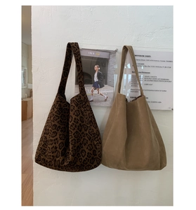Detail of leopard print and camel suede tote bags with wide shoulder straps on white wall