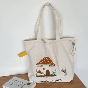 Beige canvas tote bag with mushroom house embroidery and grey drawstring closure