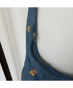 Détail du sac cabas en denim avec broderie d'escargot exquise et fermeture éclair en métal