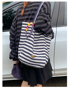 Close-up of blue striped canvas tote with handmade metal tag and colorful heart charms