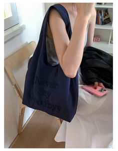 Detail of navy blue nylon tote bag showing high-quality letter embroidery and fabric texture