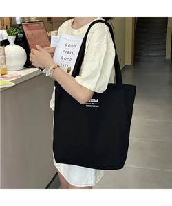 Close-up of black canvas tote bag with ZYUBAG artistic typography in a lifestyle setting