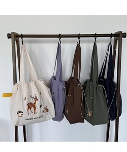 Detailed close-up of embroidered canvas tote bags in five colors with forest motifs