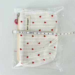 Width measurement of striped canvas heart makeup bag with pink zipper pull detail