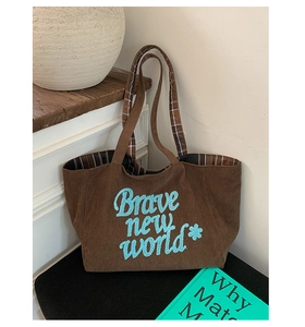 Detailed close-up of dark brown corduroy tote with floral embroidery and plaid strap design