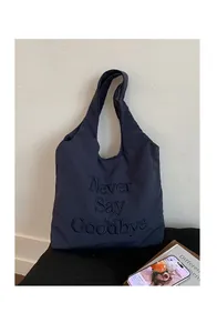 Detail of navy nylon tote bag with black Never Say Goodbye embroidery and fine texture