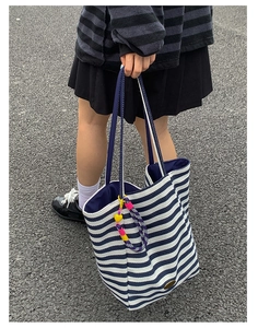 Detail of canvas tote bag with blue stripes and decorative yellow heart pendant