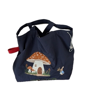 Navy canvas tote bag with mushroom house embroidery and red straps on white background