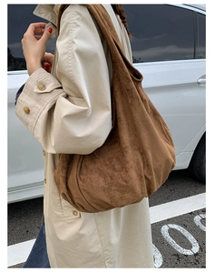 Brown suede tote bag shown on shoulder in a stylish street setting with trench coat