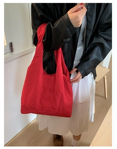 Close-up of red nylon tote bag with 3D embossed Never Say Goodbye lettering detail