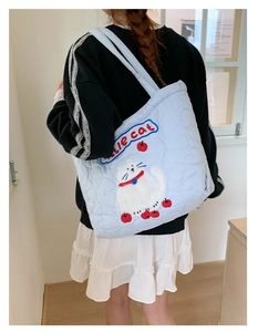 Close-up of light blue quilted tote bag with cat and cherry embroidery and little cat text
