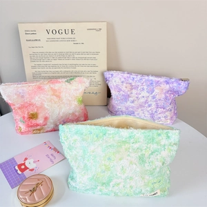 Detail of floral plush cosmetic bags with soft macaron tones and embroidery texture